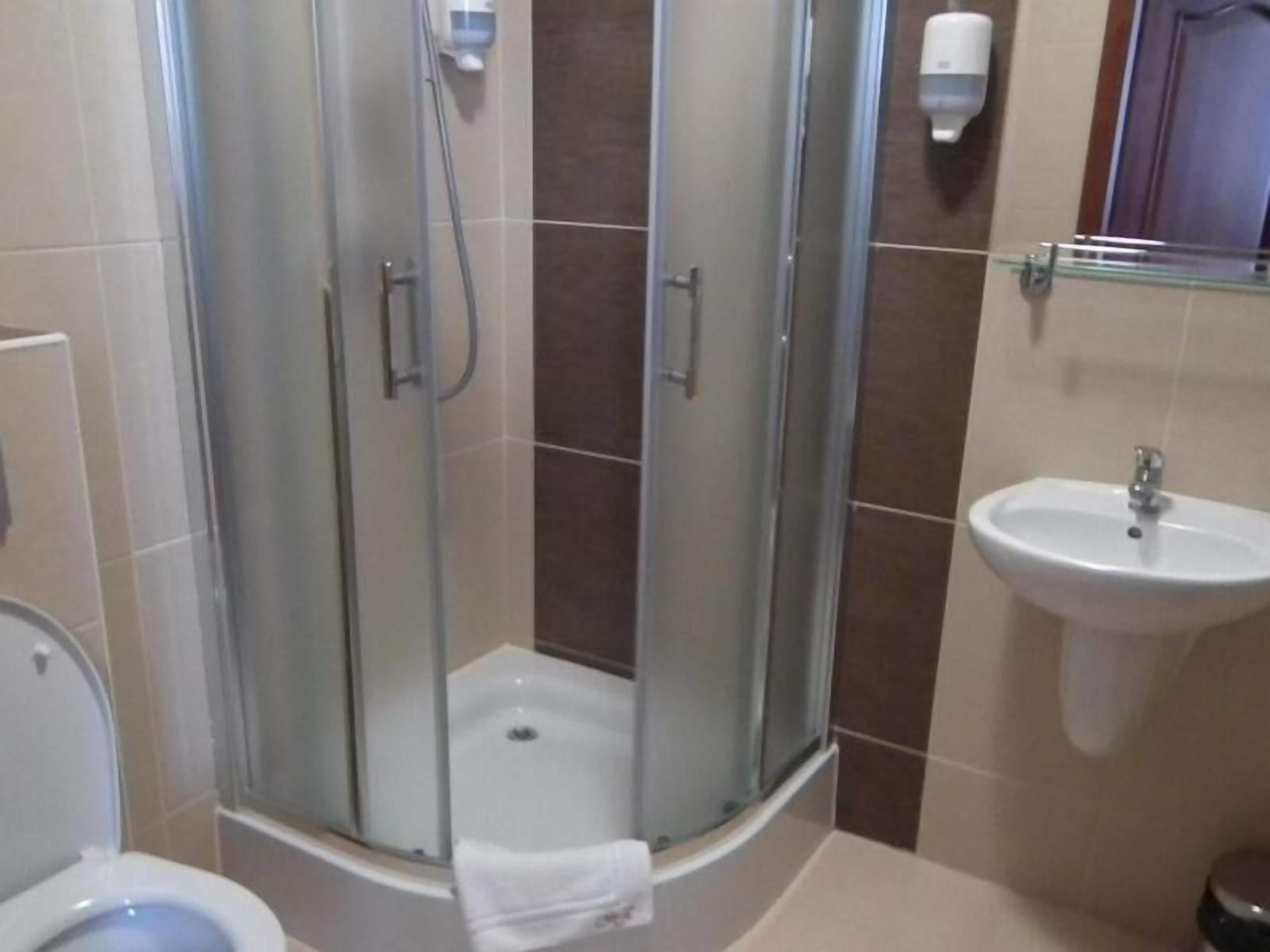 A bathroom with a glass-enclosed shower, a sink, and a toilet.