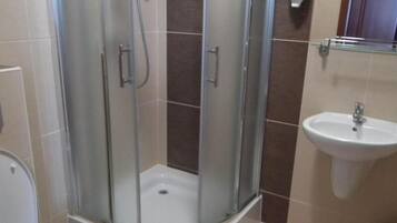 A bathroom with a glass-enclosed shower, a sink, and a toilet.