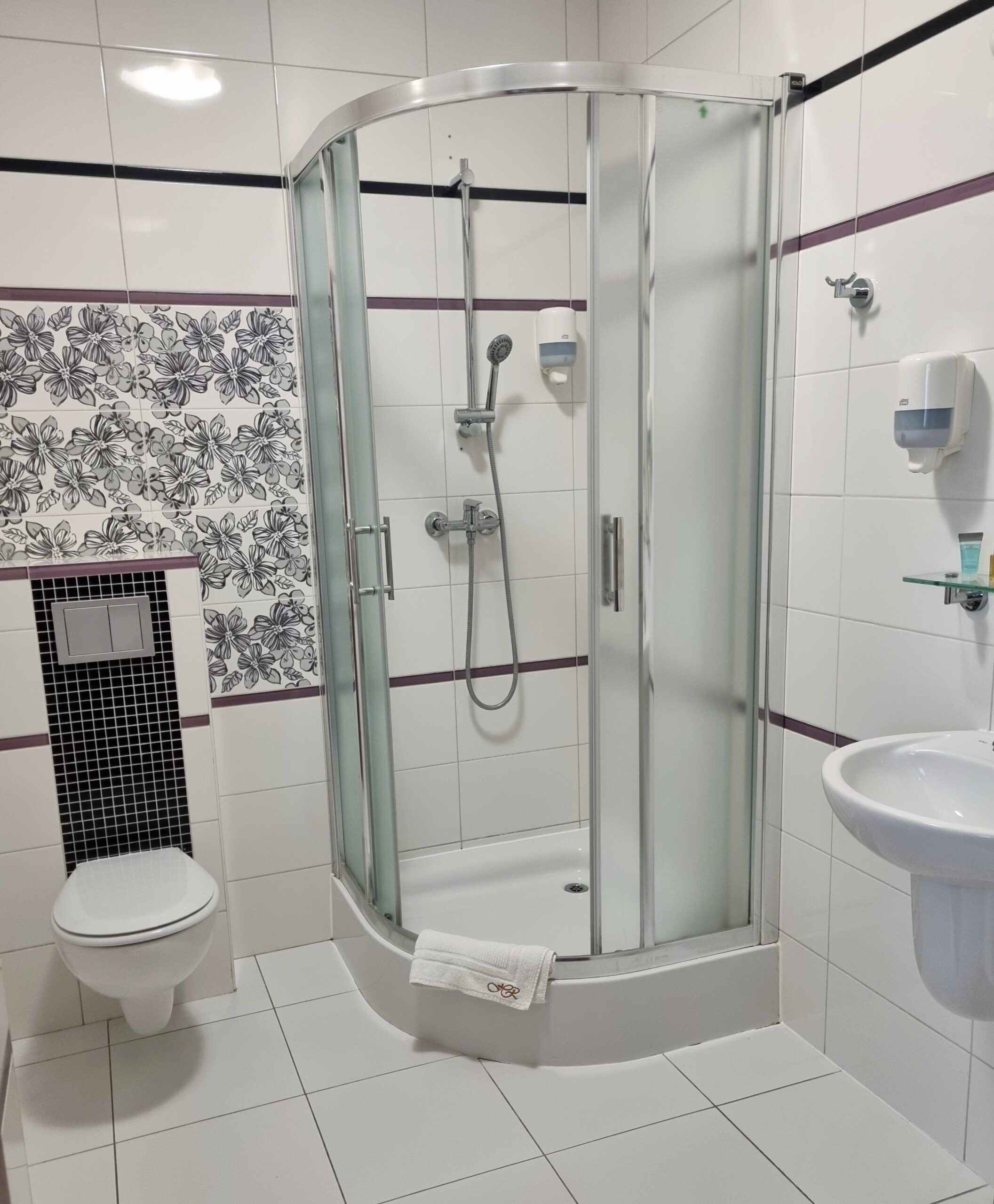 Un baño con ducha de vidrio, inodoro y lavamanos.