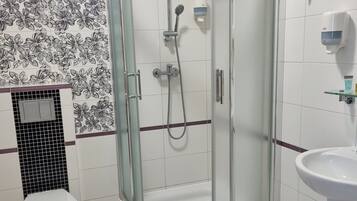 Un baño con ducha de vidrio, inodoro y lavamanos.
