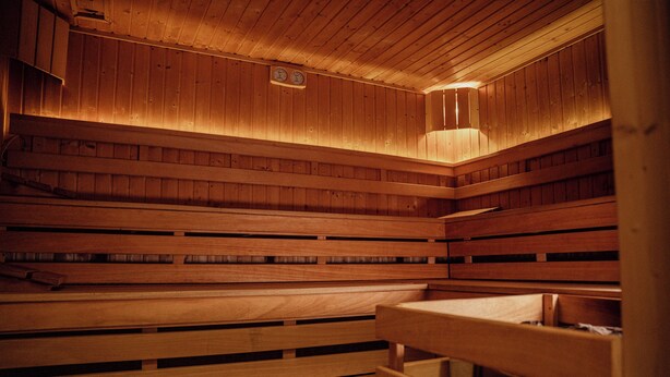 A wooden sauna with benches and a wall-mounted clock.