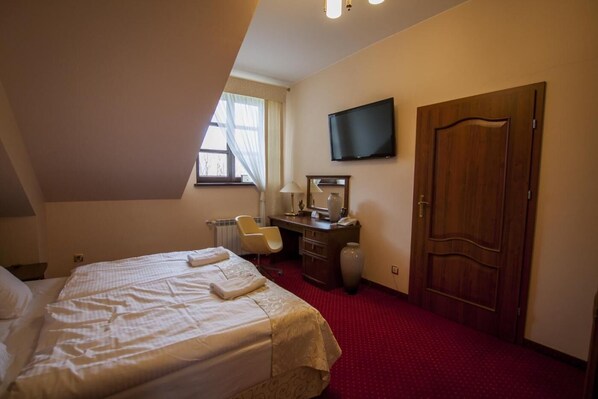 Una habitación de hotel con cama, escritorio, silla, televisión y armario.