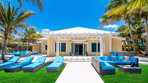 A resort with a white building, outdoor lounge area with blue furniture, and palm trees.