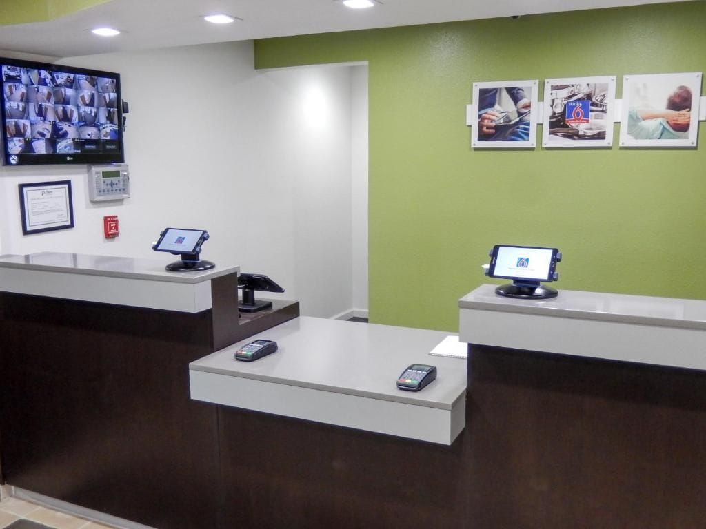 Un área de recepción con dos mostradores, un televisor montado en la pared y un detector de incendios.