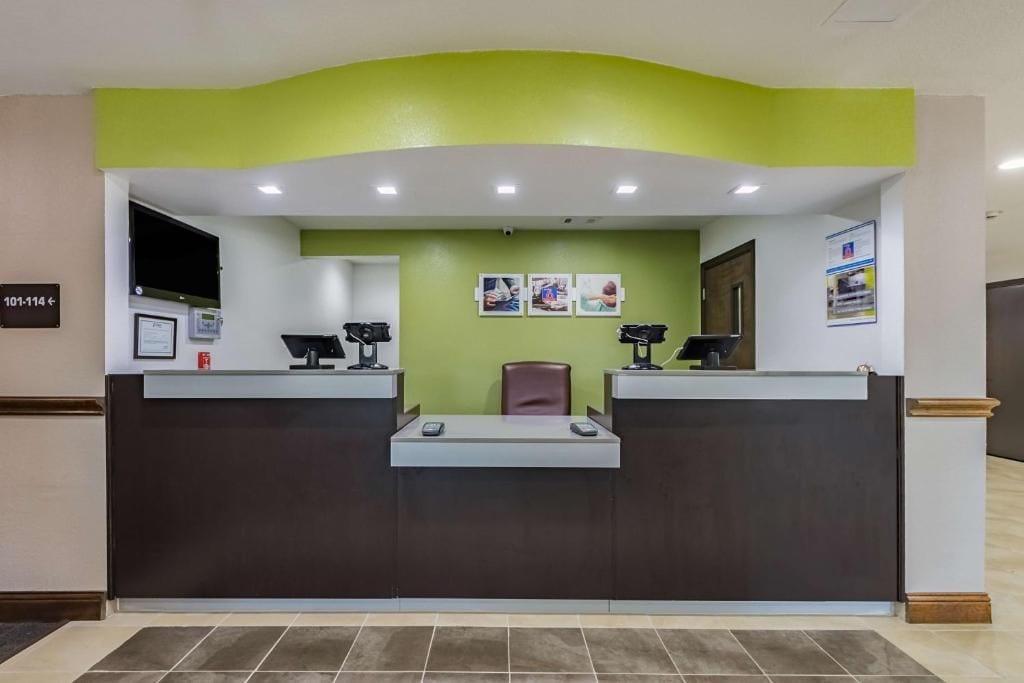 Una recepción con una pared de acento verde, una barra marrón y una silla.