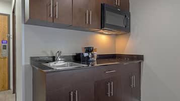Una cocina moderna con armarios de madera oscura, electrodomésticos de acero inoxidable y un microondas integrado.