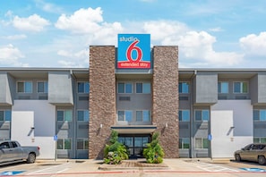 A modern hotel with a prominent '6' sign, a parking lot, and a fire lane. - Studio 6 Plano, TX (Plano)