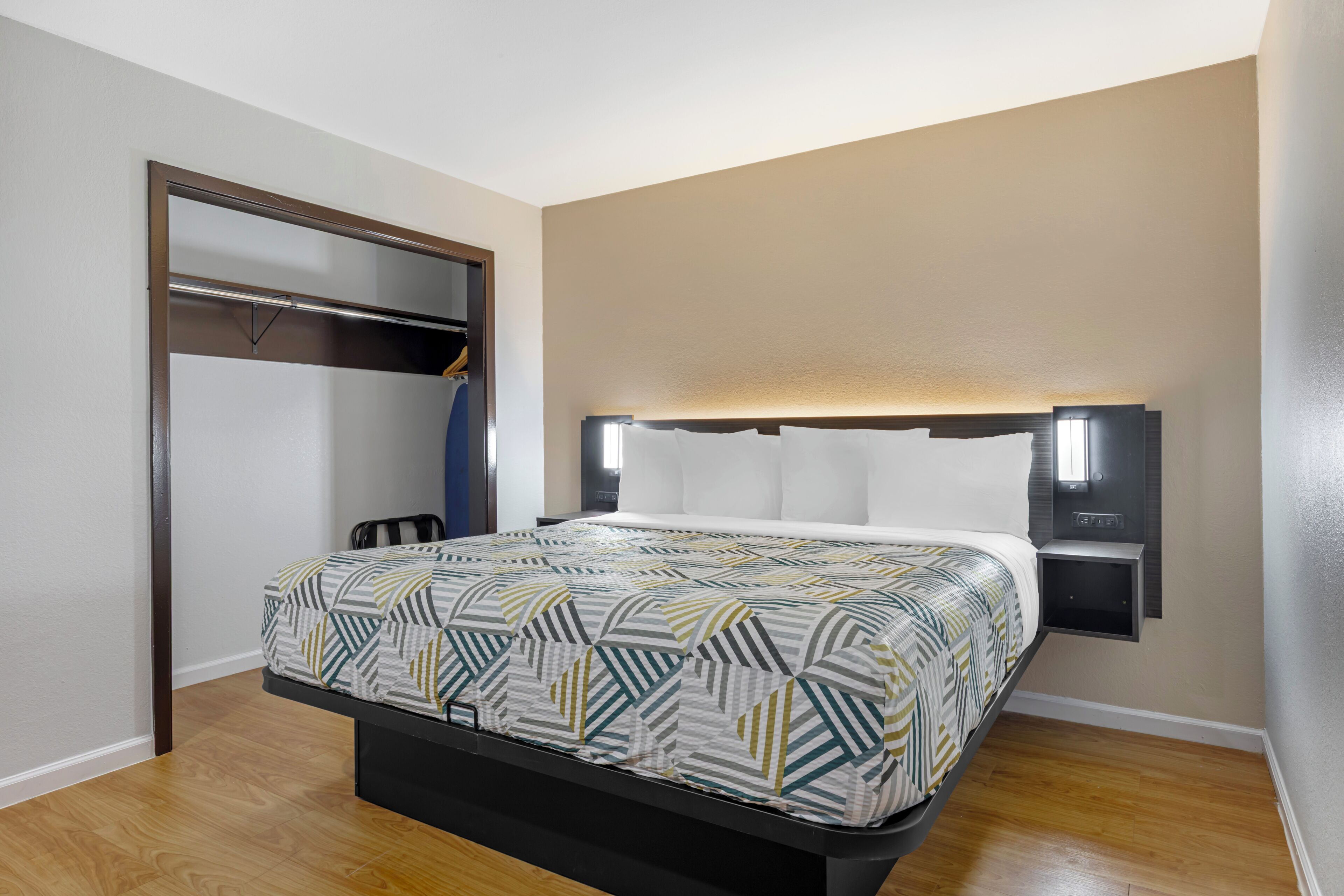 Una habitación de hotel con cama, armario y mesita de noche.