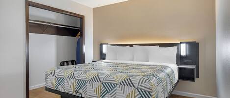 Una habitación de hotel con cama, armario y mesita de noche.