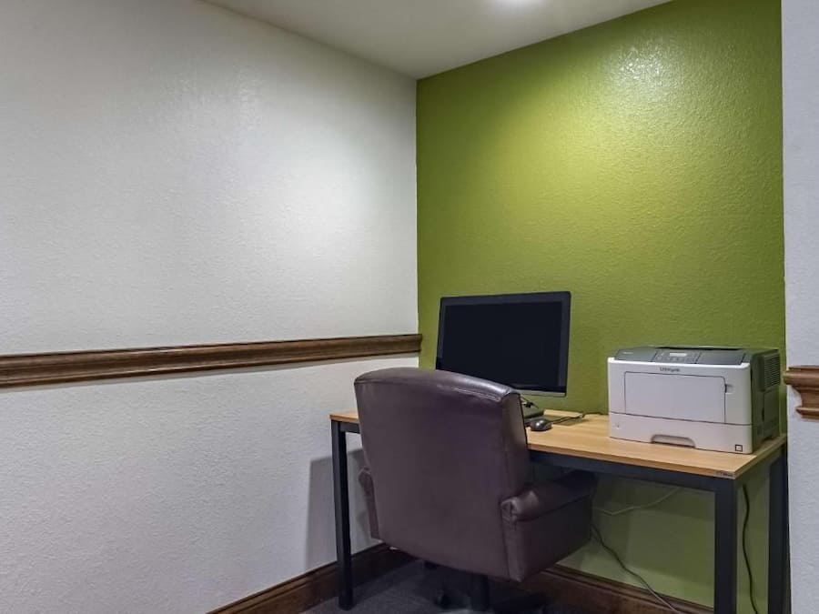 A corner office with a desk, chair, computer monitor, and printer.