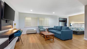 A modern living room with a flat-screen TV, a sofa, a coffee table, and a patterned armchair.