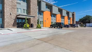 Un edificio de varios pisos con estacionamiento y varios coches.