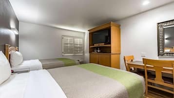 Una habitación de hotel con dos camas, un escritorio, un televisor y un espejo.