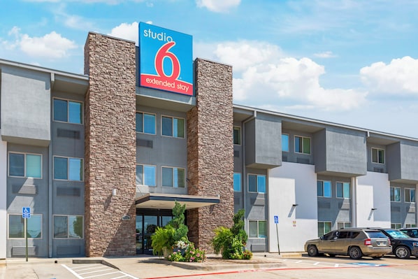 Un hotel de varios pisos con un llamativo letrero que dice 'Studio 6 Extended Stay'.