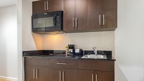 Cocina compacta con microondas, estufa, pileta y armarios de madera.