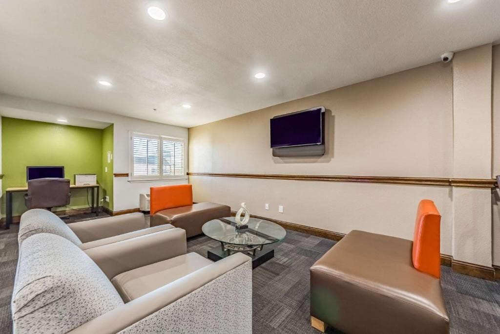 Una habitación de hotel con sofá, sillón, reposapiés y una mesita de centro.