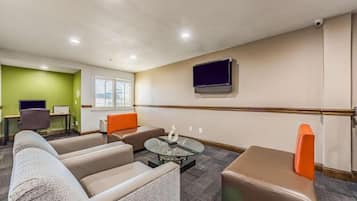 Una habitación de hotel con sofá, sillón, reposapiés y una mesita de centro.