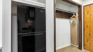 Cocina compacta con refrigerador negro, puerta de madera y un perchero.