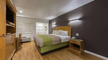 Una habitación de hotel con cama, mesita de noche y escritorio.