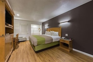 Una habitación de hotel con cama, mesita de noche y escritorio.