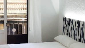 Et hotelværelse med en seng, et vindue med udsigt til en balkon og en dør.