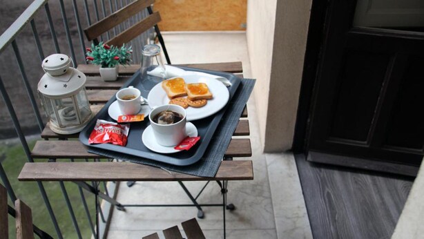 A balcony table with a tray holding a cup of coffee, two slices of toast, a packet of sugar, and a small bowl of jam. - B&B del Toscano (Catania)