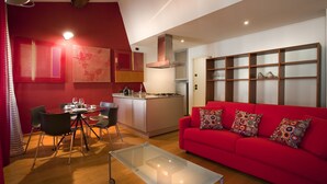 Ein modernes Wohnzimmer mit einem roten Sofa, einem Glastisch und einem Essbereich mit Stühlen und einem Tisch.