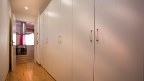 Ein schmaler Flur mit Holzboden führt zu einer Küche mit weißen Schränken und einer Edelstahl-Dunstabzugshaube.