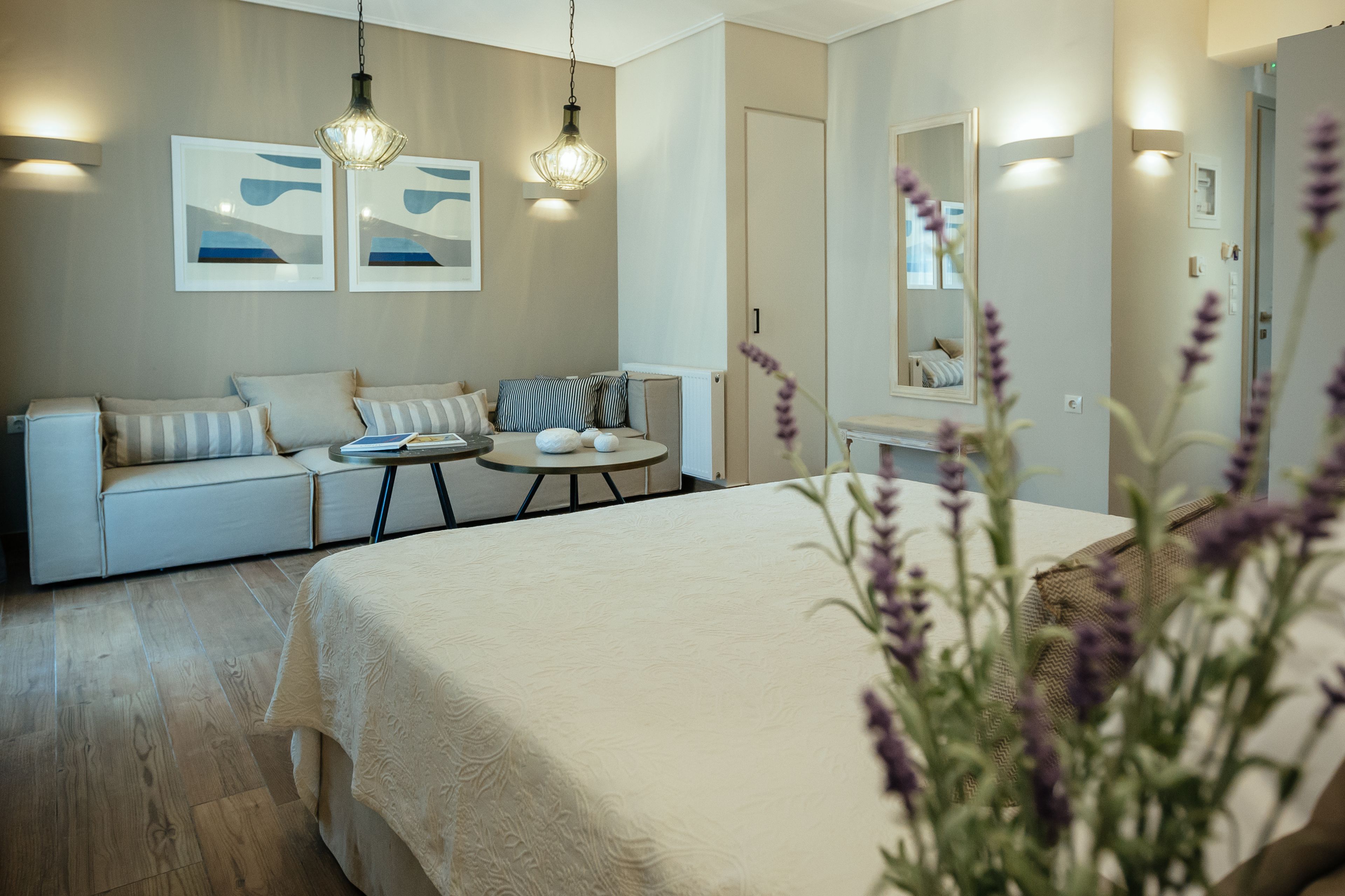 Un dormitorio moderno con una cama grande, un sofá, una pequeña mesa redonda y dos lámparas colgantes.