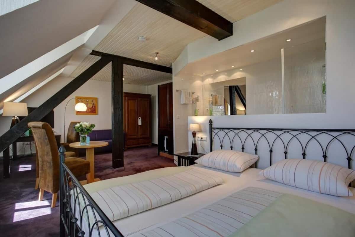 A bedroom with a bed, a nightstand, a lamp, a chair, and a small table.