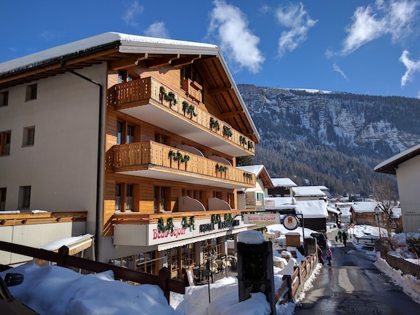 Un immeuble en bois à plusieurs étages, doté de balcons, d’un restaurant et d’une enseigne indiquant qu’il s’agit d’un hôtel.