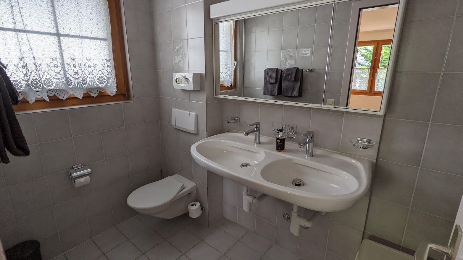 A bathroom with a toilet, sink, and mirror.