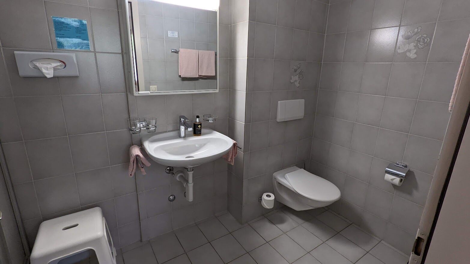Een compacte, moderne badkamer met een wastafel, toilet en spiegel.