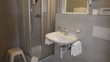 Une salle de bain avec une douche à parois de verre, un lavabo, des toilettes et un miroir.