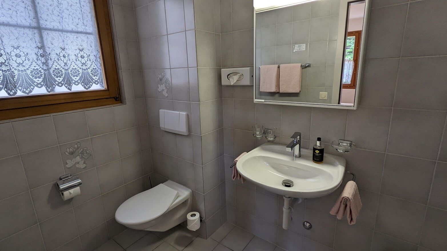 A bathroom with a toilet, sink, and mirror.