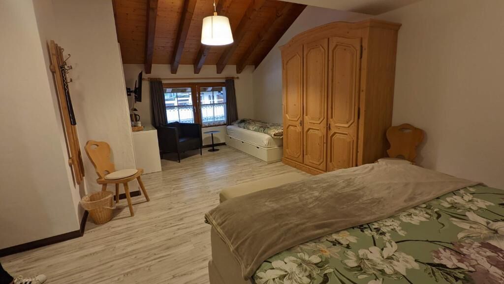 A bedroom with a bed, wooden wardrobe, and a chair.