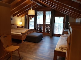 Una habitación acogedora con cama, una silla, un escritorio y un balcón con barandillas de madera.