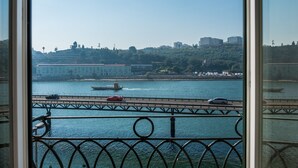 A view from a window overlooking a bridge with vehicles crossing over a river, with buildings and greenery in the background. - Vila Gale Porto Ribeira Hotel (Porto)