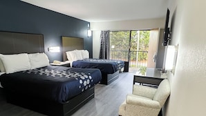 A hotel room with two beds, a chair, a TV, and a balcony with a view of trees. - Travel Inn (New Castle)