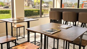 A modern hotel room with large windows, a wooden table, and a bench. - Travel Inn (New Castle)