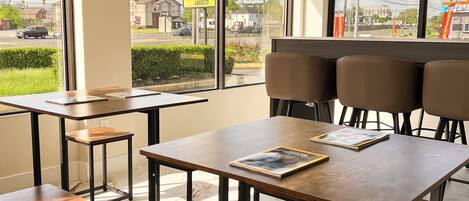 Una habitación de hotel moderna con ventanas amplias, una mesa de madera y un banco.
