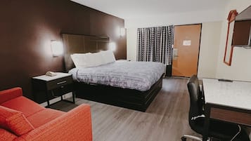Una habitación de hotel moderna con una cama grande, un escritorio, un sofá rojo y un espejo.