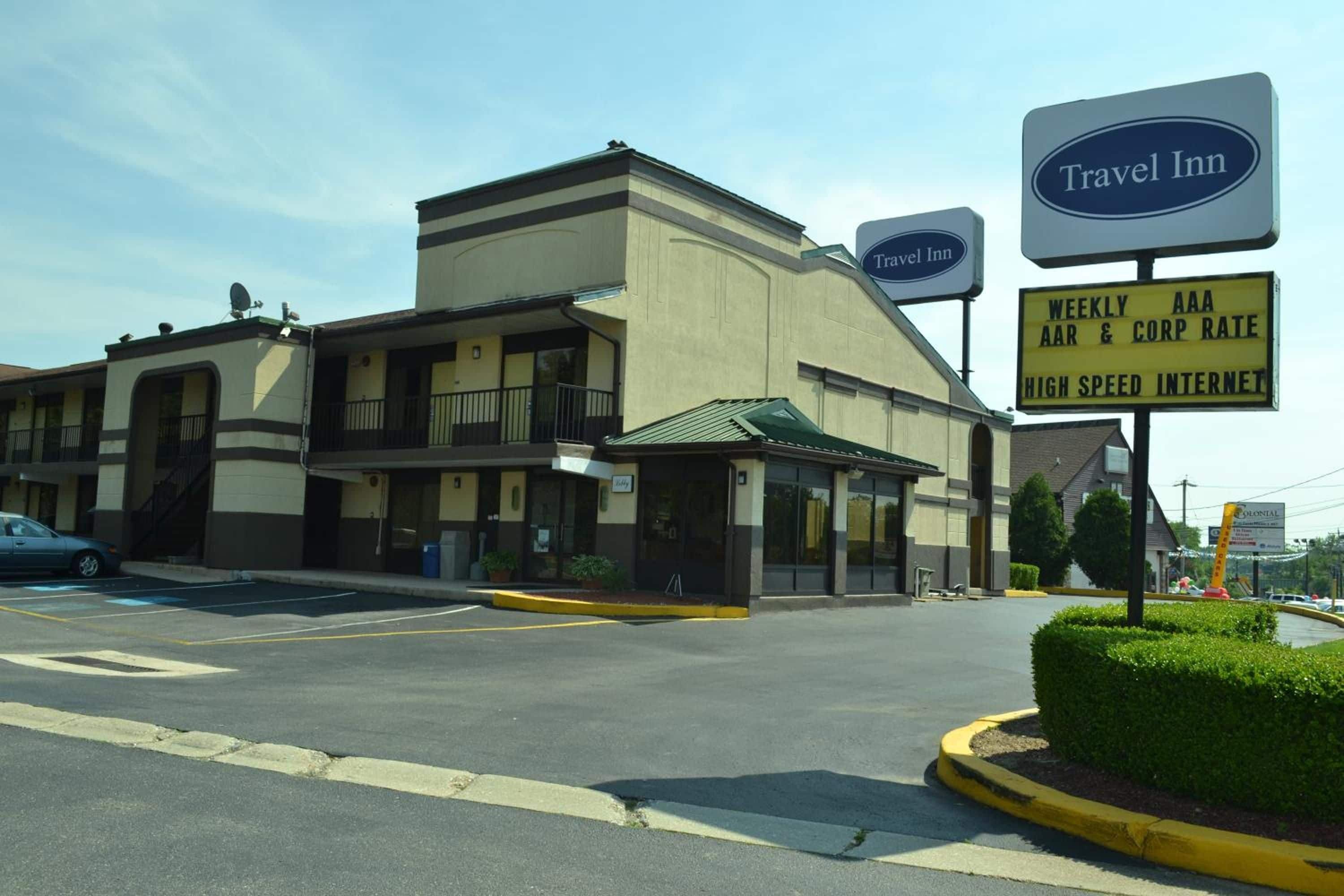 A Travel Inn hotel with a parking lot and a sign indicating weekly AAA rates and high-speed internet.