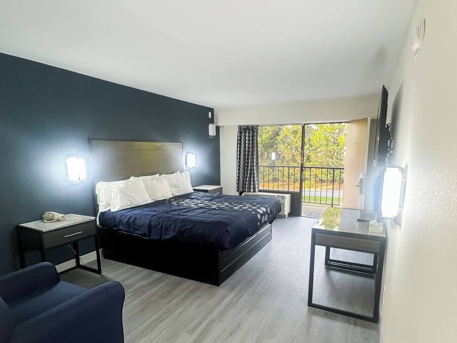 Una habitación de hotel moderna con cama, mesitas de noche, un escritorio, una silla y televisión.
