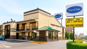 A Travel Inn hotel with a two-story structure, a covered entrance, and a sign indicating weekly AAA and corporate rates with high-speed internet. - Travel Inn (New Castle)