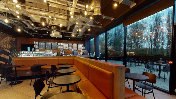 Ein modernes Café-Interieur mit Sitzgelegenheiten, Tischen und einer Theke mit Speisekarten.