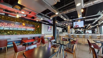 A modern restaurant interior with booths and tables, a bar area, and a television screen.