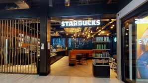 Ein Starbucks mit modernem Interieur, Sitzgelegenheiten und Blick auf die Stadt.
