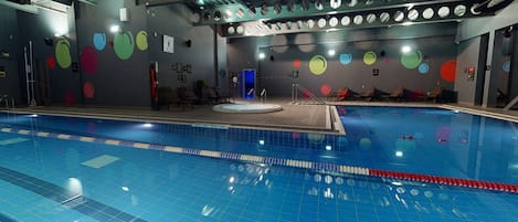 Une piscine dont le sol est carrelé et dont le plafond est orné de miroirs circulaires.