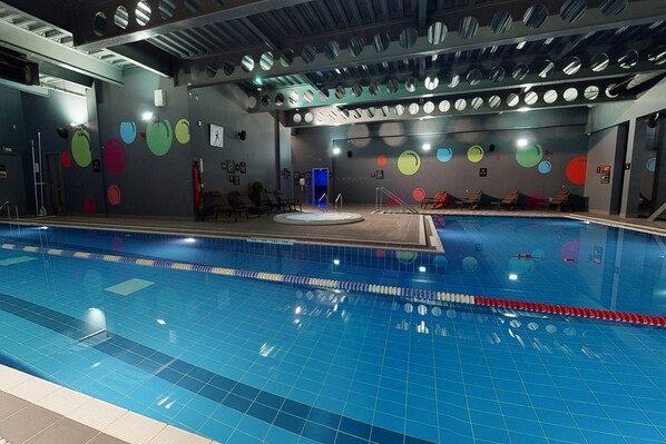 A swimming pool with a tiled floor and a ceiling with circular mirrors.